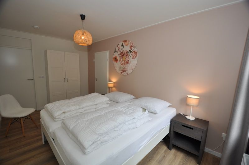 Ruime slaapkamer in Bungalow Verste Coogh 62, De Dennen, Texel met comfortabele bedden en rustgevende inrichting.