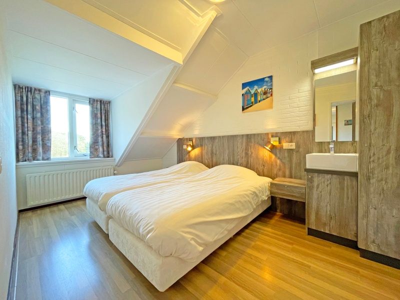 Slaapkamer met twee bedden in Appartement Bos en Duin 36, De Dennen, Texel met sfeervolle verlichting.
