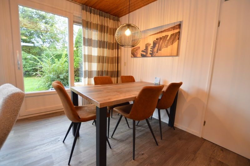 Essecke im Ferienhaus de Parel 234 in De Dennen, Texel mit Holztisch und Stuehlen.