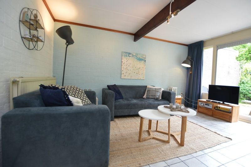 Gezellige woonkamer in Bungalow Verste Coogh 56, De Dennen, Texel, met comfortabele banken en uitzicht op de natuur.
