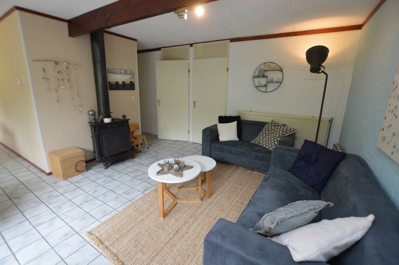 Knusse binnenruimte in Bungalow Verste Coogh 56, De Dennen, Texel, met houtkachel voor gezellige avonden.