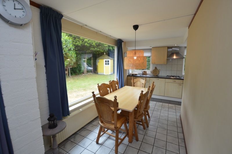 Eethoek in Bungalow Verste Coogh 56, De Dennen, Texel, met uitzicht op de tuin, ideaal voor gezellige maaltijden.