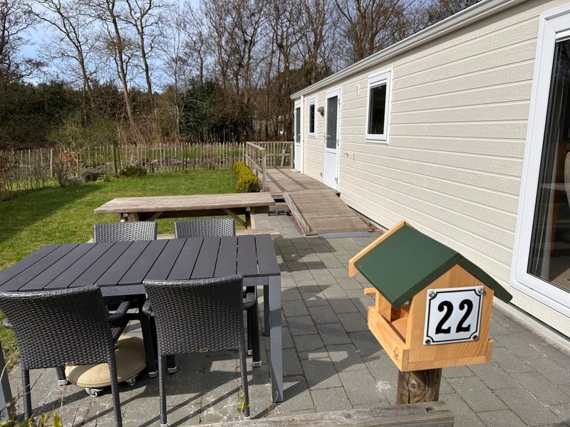 Ferienpark De Bremakker - Chalet Skeep in De Dennen, Texel, mit sonniger Terrasse und gruener Umgebung, ideal fuer einen entspannten Aufenthalt.