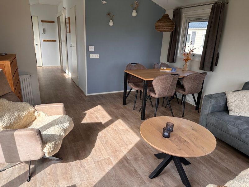 Gemuetliches Wohnzimmer im Chalet Skeep im Ferienpark De Bremakker, De Dennen, Texel. Komfortable Sitzecke und Essbereich in heller Umgebung.