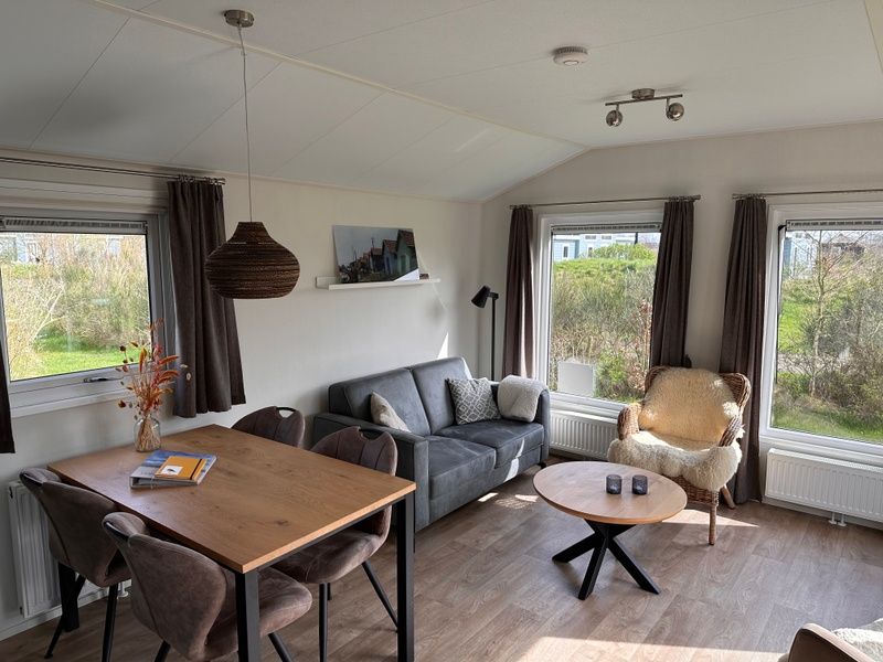 Gemuetliches Wohnzimmer im Chalet Skeep im Ferienpark De Bremakker, De Dennen, Texel. Komfortabler Sitzbereich mit Blick auf die Natur.