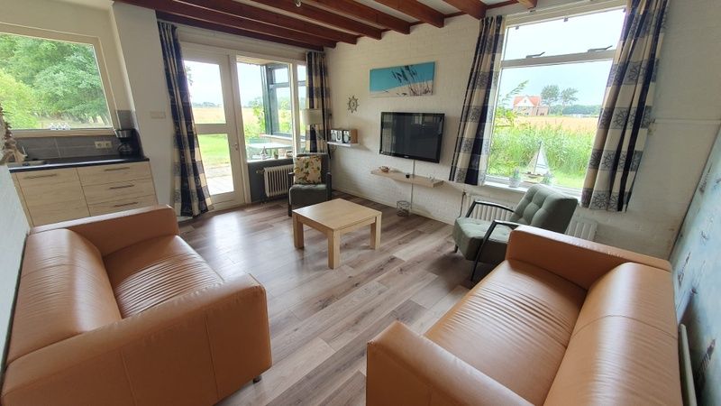 Gezellige woonkamer van Weizicht Texel vakantiehuis in De Dennen, Texel, met moderne inrichting en uitzicht op de groene natuur.