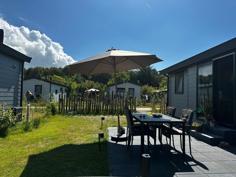Geraeumige Terrasse mit Sonnenschirm im Vakantiepark de Bremakker - Chalet Wulk, De Dennen, Texel, ideal fuer Mahlzeiten im Freien.