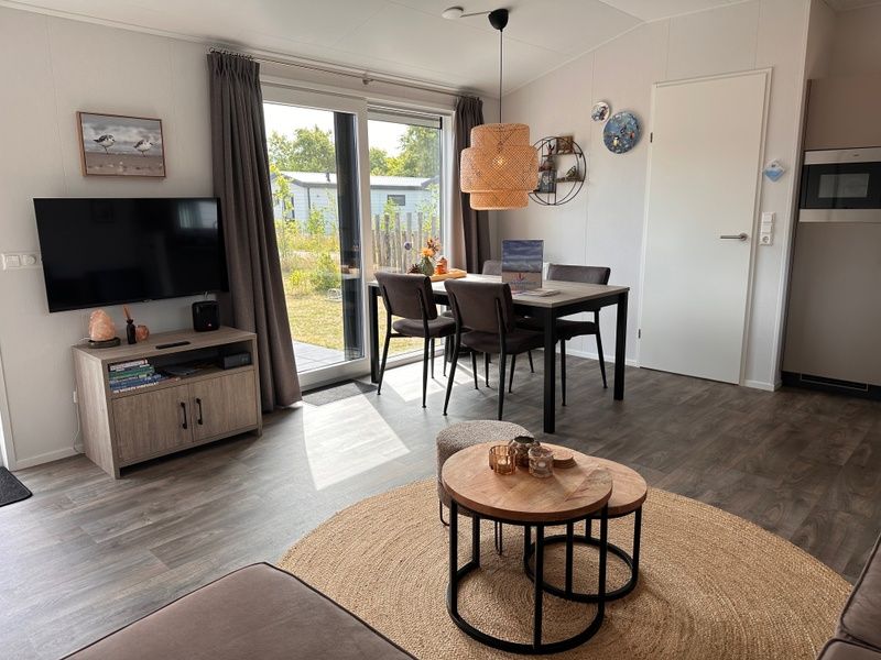 Stilvolles Wohnzimmer des Chalets Wulk im Vakantiepark de Bremakker, Texel, mit moderner Einrichtung und Gartenblick.