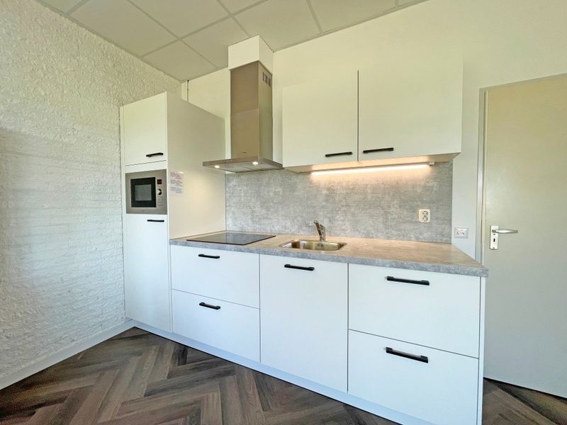 Kompakte Kueche im Appartement Bos en Duin 02, De Dennen, Texel mit modernen Geraeten und viel Stauraum.