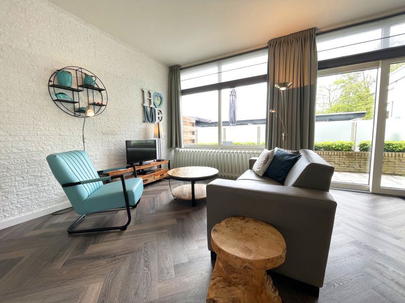 Gemuetliche Sitzecke im Apartment Bos en Duin 03, De Dennen, Texel mit bequemem Sessel und Blick auf die Terrasse.