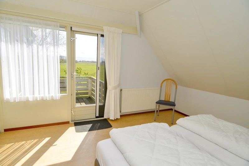 Schlafzimmer im Ferienhaus Roodborstje, De Dennen, Texel mit Balkon und schoener Aussicht.