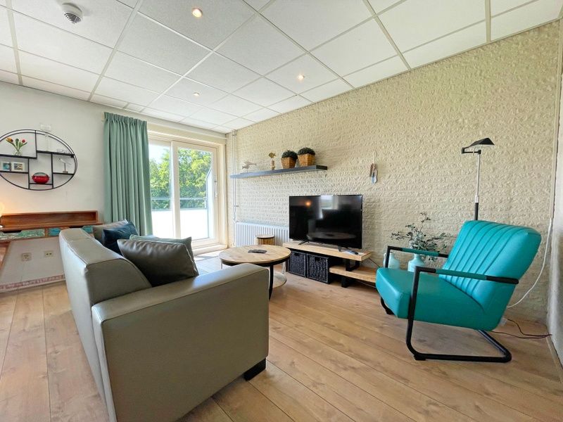 Geraeumiges Interieur des Apartments Bos en Duin 16 in De Dennen Texel mit Blick auf die gruene Umgebung.