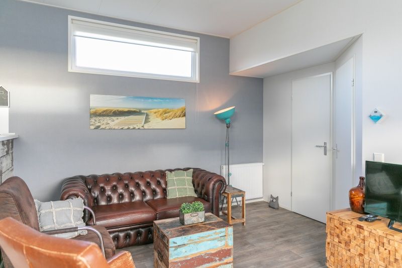 Gezellige woonkamer in Chalet Julie van Vakantiepark de Bremakker, gelegen in De Dennen, Texel. Comfortabel interieur met stranddecoratie.