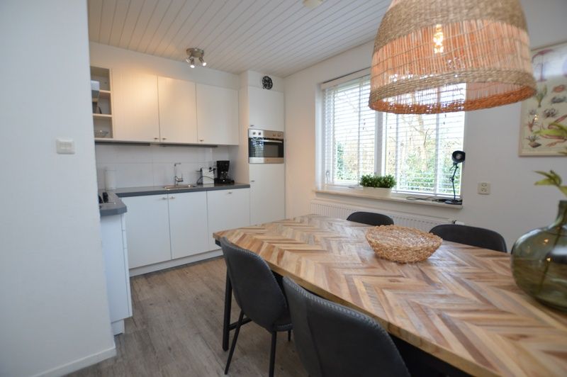 Dining room and kitchen in vacation home Gerritslanderdijkje 146 - Salty Dog, De Dennen, Texel with wooden dining table.