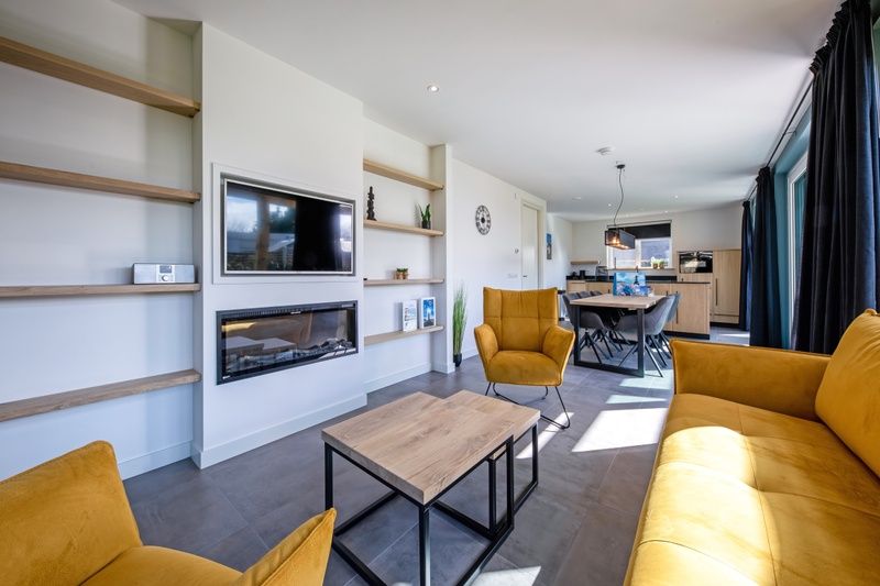 Offenes Wohnzimmer und Kueche im Ferienhaus im Bungalowpark 't Luwe Land, Nieuw Vredelust, Texel, mit moderner Einrichtung.