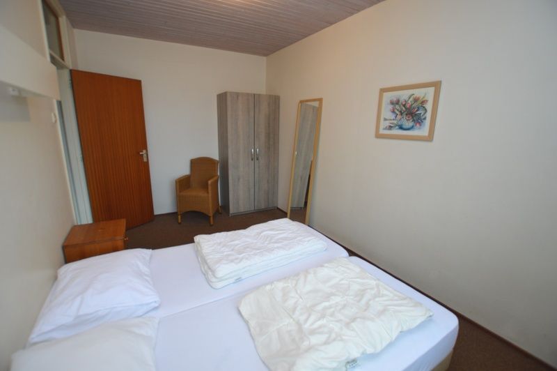 Rustige slaapkamer in vakantiehuis Anjer, De Dennen, Texel met spiegel en kast.