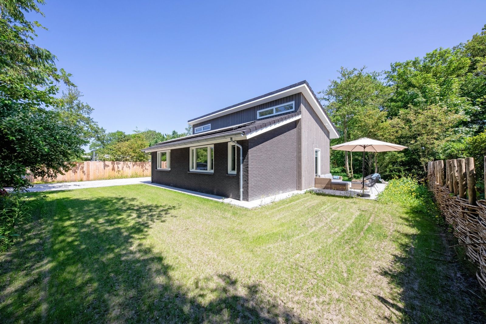 Zijaanzicht van Tormentil vakantiewoning in De Dennen, Texel met groene omgeving.