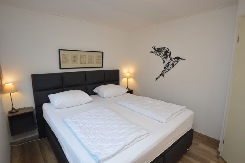 Slaapkamer in Vakantiehuis de Parel 244, De Dennen, Texel met comfortabel bed en sfeervolle verlichting.