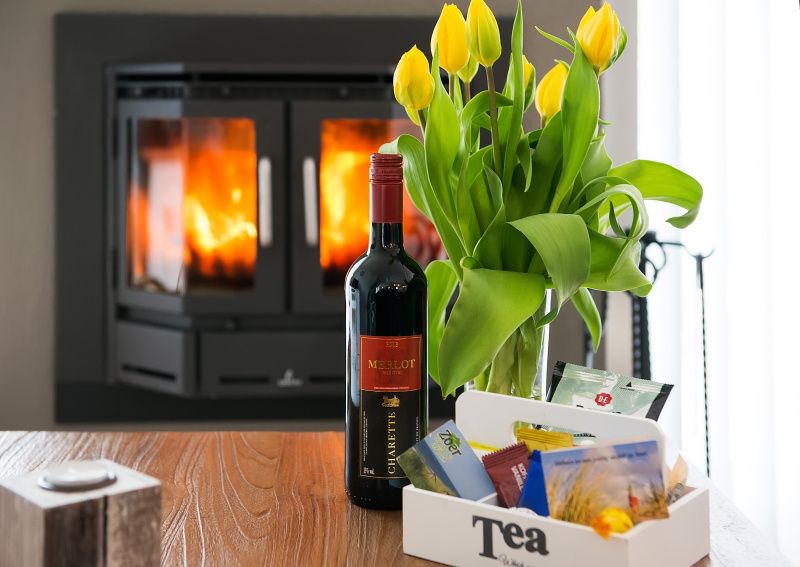 Gezellige details in de woonkamer van Gortersmient 278, Bungalowpark Gortersmient, De Dennen, Texel, met wijn en tulpen.