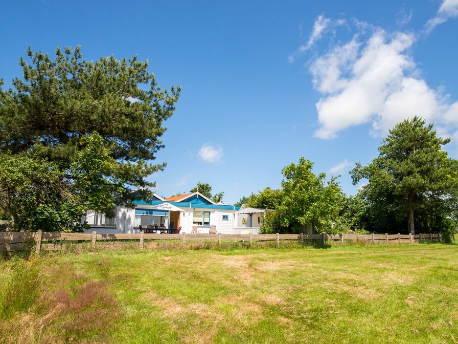 Meadow View vacation home in De Dennen, Texel overlooking green meadow and blue sky.