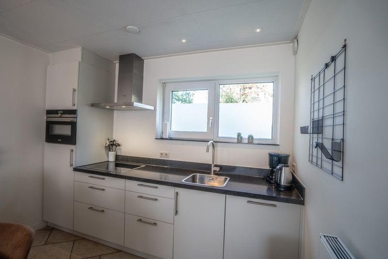 Fully equipped kitchen of Holiday Home 't Hoogelandt 136A in De Dennen, Texel with modern appliances.