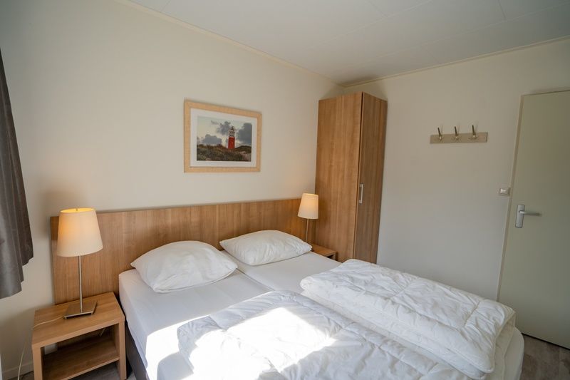 Bright bedroom of Holiday Home 't Hoogelandt 136A in De Dennen, Texel with wooden interior.