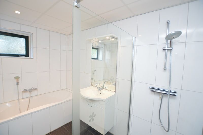 Modernes Badezimmer mit Badewanne und Dusche im Ferienhaus 't Hoogelandt 36, Texel.
