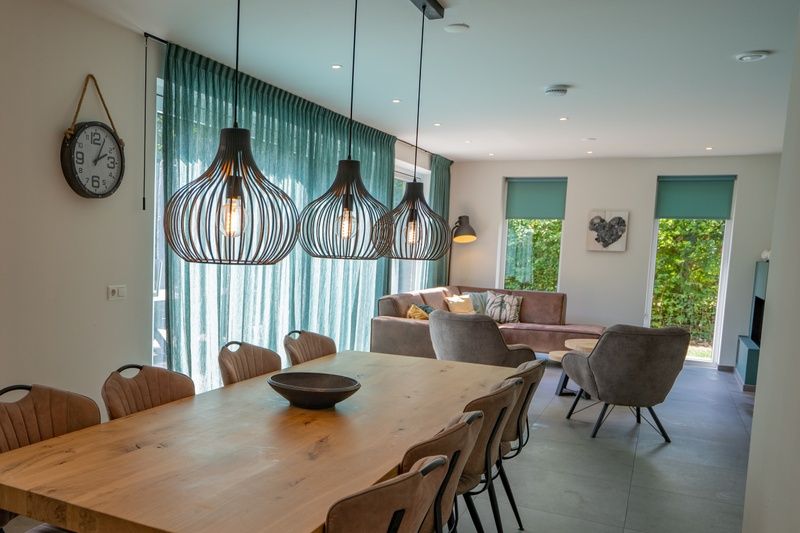 Geraeumiges Esszimmer im Ferienhaus de Parel 174, De Dennen, Texel mit moderner Beleuchtung und Sitzecke.
