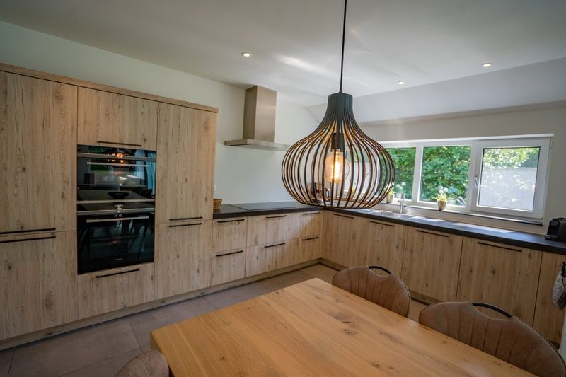 Stilvolle Kueche im Ferienhaus de Parel 174, De Dennen, Texel mit Holzschraenken und viel Licht.