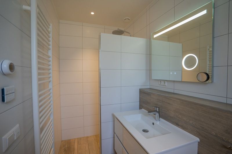 Modernes Badezimmer mit Dusche und Waschbecken im Ferienhaus de Parel 174, De Dennen, Texel.
