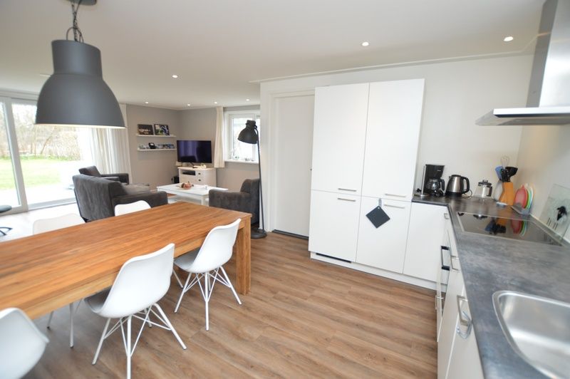 Essecke im Ferienhaus de Parel 168, De Dennen, Texel, mit grossem Tisch und moderner Kuecheneinrichtung.