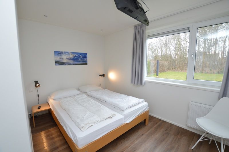 Schlafzimmer im Ferienhaus de Parel 168, De Dennen, Texel, mit bequemen Betten und Blick auf die Natur.