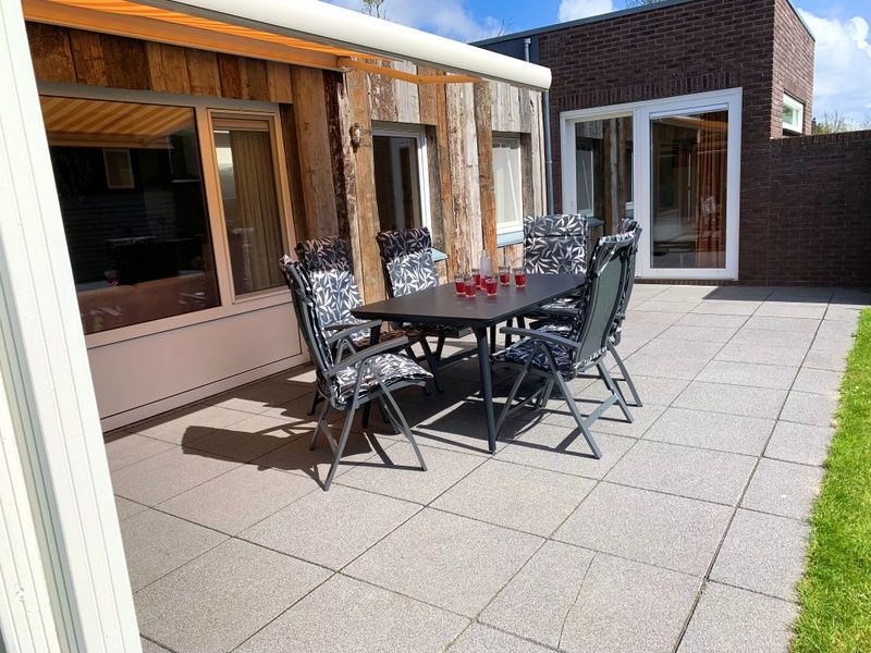 Sonnige Terrasse am Ferienhaus Hesselte in De Dennen, Texel mit Gartentisch.