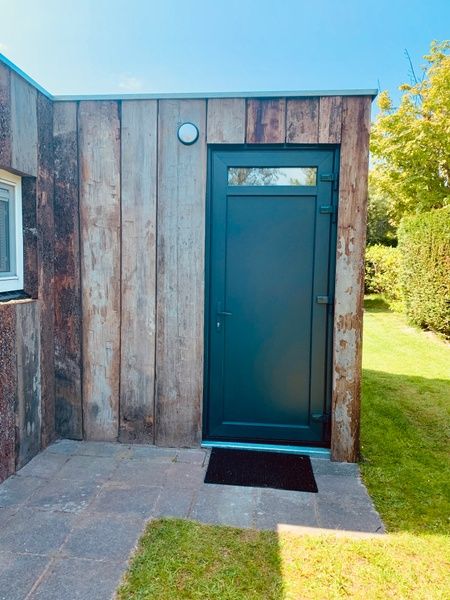 Eingang zum Ferienhaus Hesselte in De Dennen, Texel, mit Holzfassade.