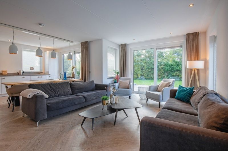 Gemuetliches Wohnzimmer in der Villa Bloem en Bos, Bungalowpark 't Hoogelandt, De Dennen, Texel, mit bequemen Sofas und Blick auf den Garten.