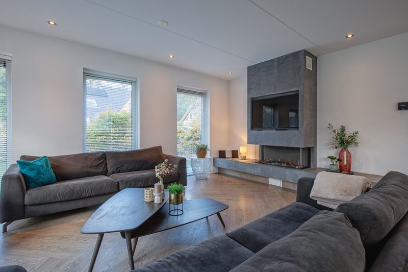 Luxurioese Sitzecke mit Kamin in der Villa Bloem en Bos, Bungalowpark 't Hoogelandt, De Dennen, Texel, ideal fuer gemuetliche Abende.