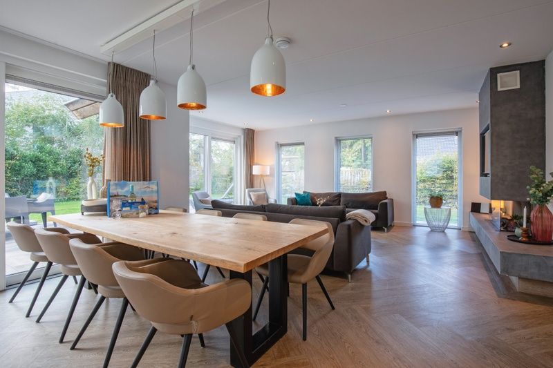 Geraeumiger offener Wohnraum in der Villa Bloem en Bos, Bungalowpark 't Hoogelandt, De Dennen, Texel, mit Zugang zum Garten und Essbereich.