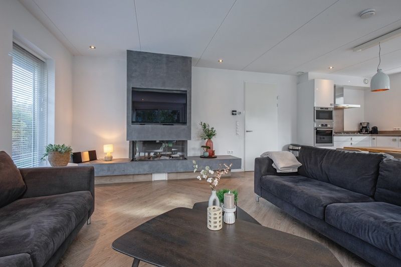 Stilvolles Wohnzimmer in der Villa Bloem en Bos, Bungalowpark 't Hoogelandt, De Dennen, Texel, mit Kamin und bequemen Sofas.