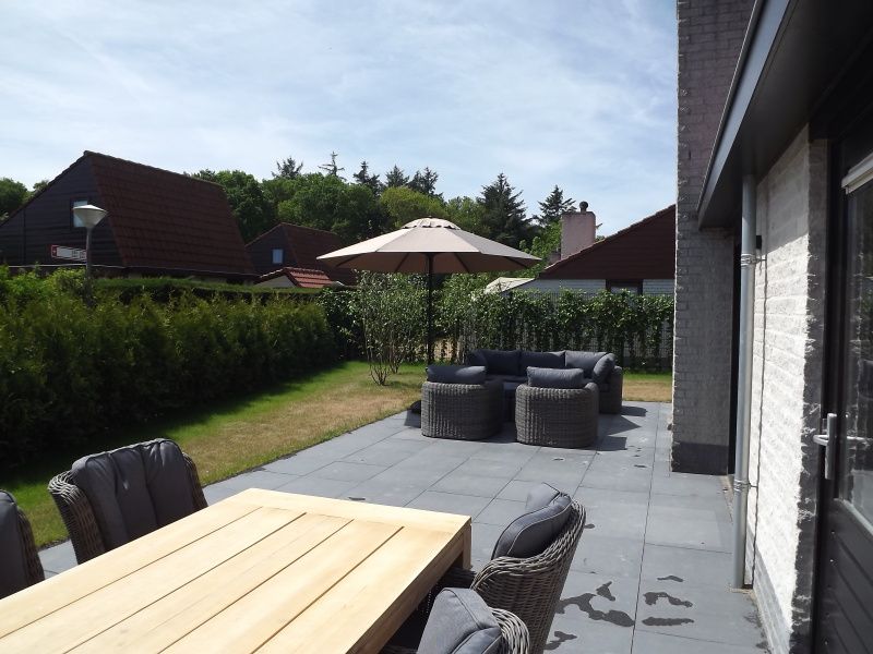 Uitzicht op het groene terras van Vakantiehuis Gortersmient 322 in De Dennen, Texel, met moderne tuinmeubels.