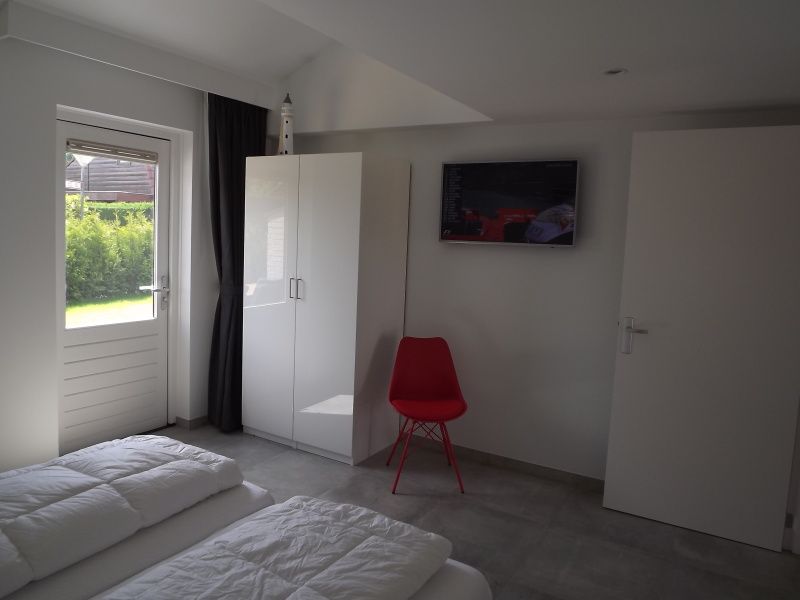 Stijlvolle slaapkamer in Vakantiehuis Gortersmient 322, De Dennen, Texel, met tv en comfortabele zitplaats.
