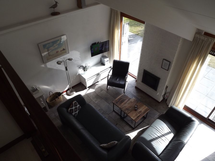 Gemuetliches Wohnzimmer im Ferienhaus Gortersmient 326, De Dennen, Texel mit bequemen Sitzgelegenheiten und Kamin.