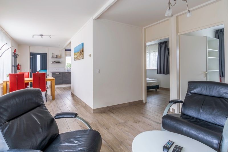 Open leefruimte in Bungalowpark 't Luwe Land, Texelfan, De Dennen, Texel. Ruime woonkamer met toegang tot de slaapkamer in de vakantiewoning.