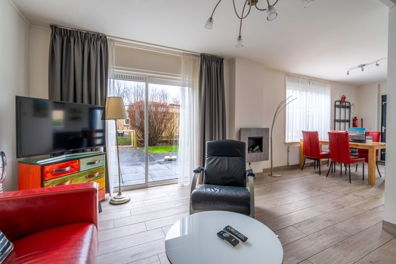 Lichte woonkamer in Bungalowpark 't Luwe Land, Texelfan, De Dennen, Texel. Moderne inrichting en uitzicht op de tuin vanuit de vakantiewoning.