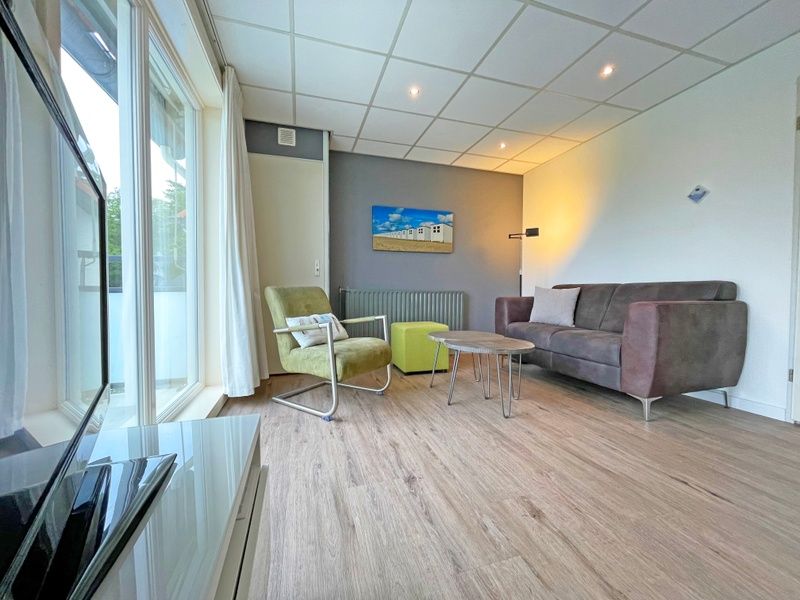 Stilvolle Sitzecke im Appartement Bos en Duin 19, Texel mit modernen Moebeln und Kunst an der Wand.
