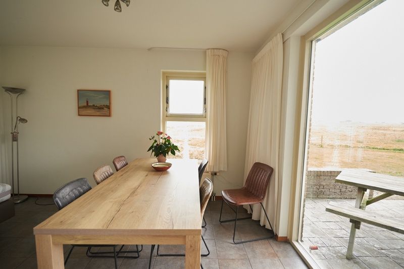 Essecke im Ferienhaus De Mispel, De Dennen, Texel mit grossen Fenstern und viel Licht.