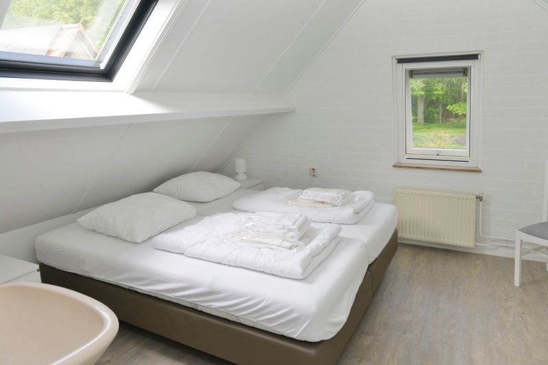 Ruime slaapkamer in vakantiehuis Turel, De Dennen, Texel met uitzicht op bos.