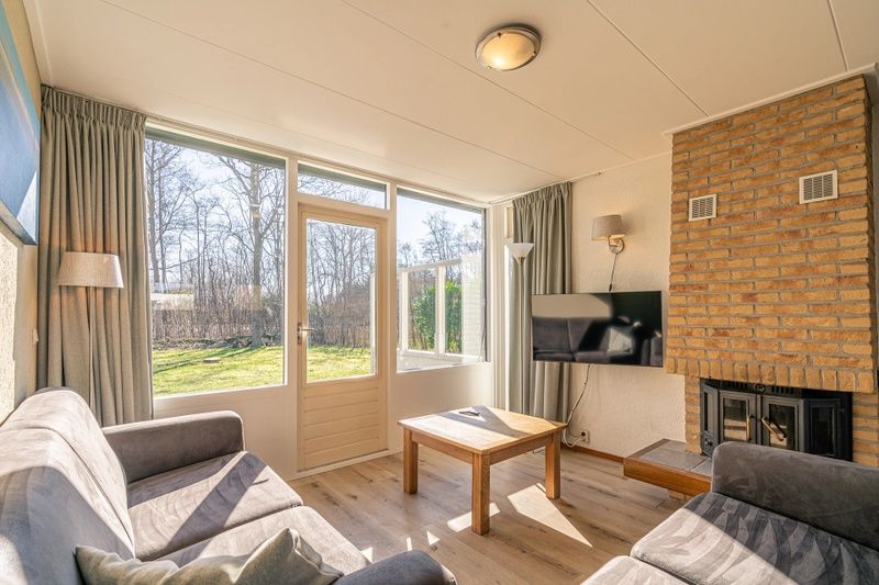 Heller Wohnbereich im Ferienhaus de Parel 166, De Dennen, Texel. Blick auf den Garten von der gemuetlichen Sitzecke aus.