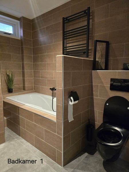 Luxurioeses Badezimmer im Helianthus Ferienhaus De Dennen Texel mit Badewanne und moderner Toilette.