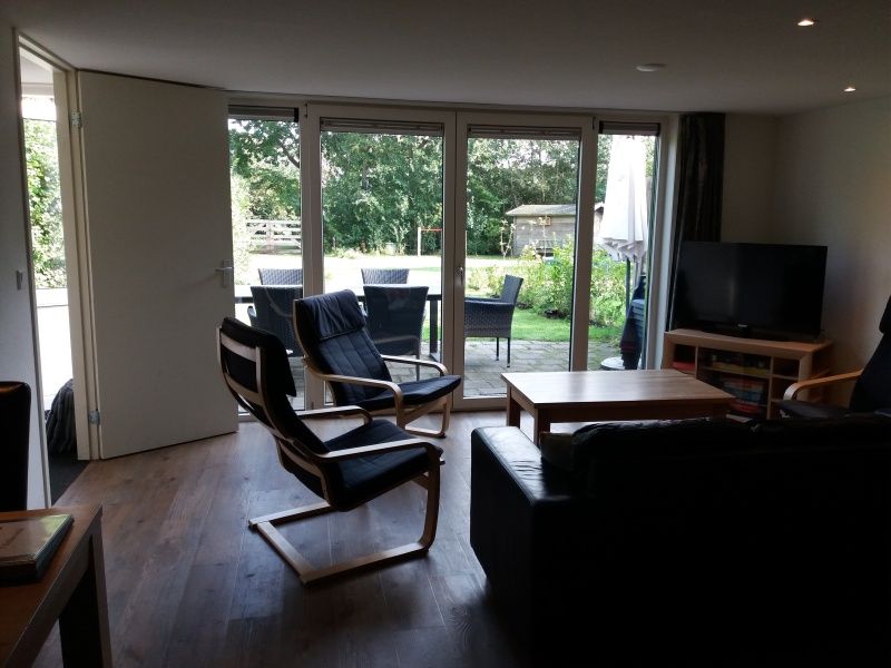 Helles Wohnzimmer in Bollenveld - die Iris, Ferienhaus De Dennen, Texel mit Blick auf gruenen Garten und Terrasse.