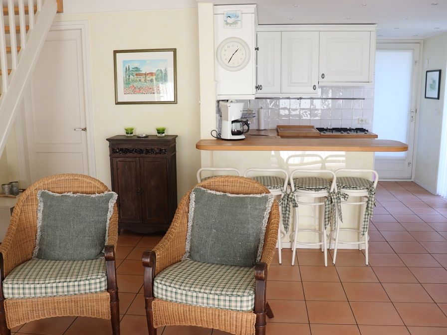 Gezellige binnenruimte in Vakantiehuis Gortersmient 264, De Dennen, Texel met rieten stoelen en keuken.